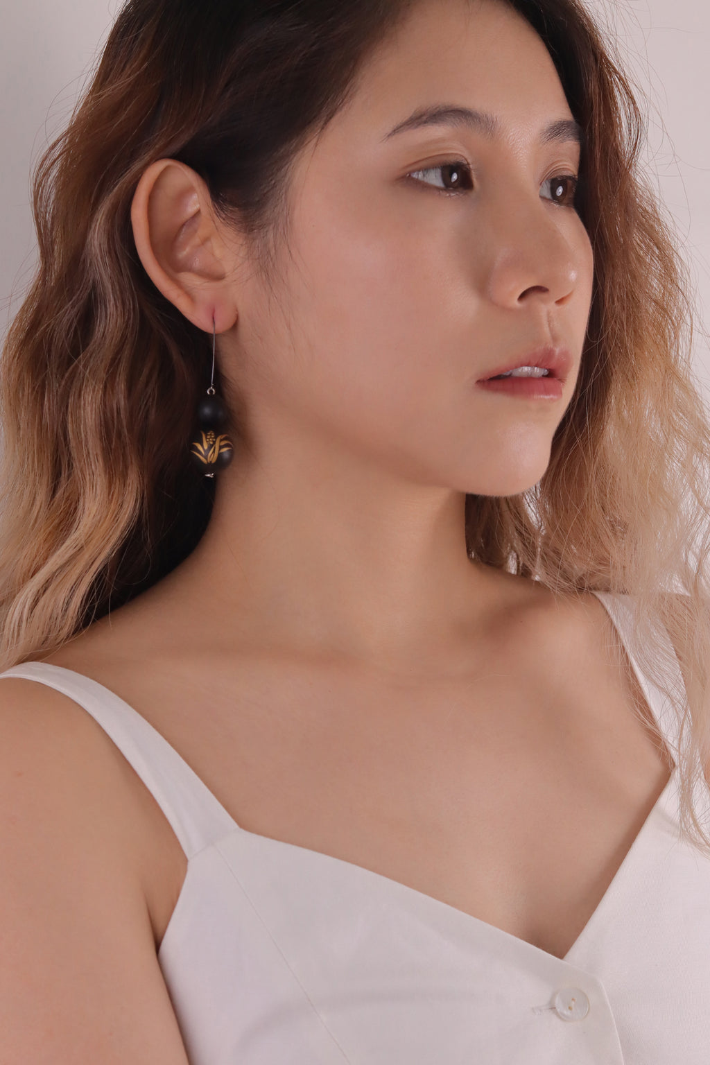 Acorus Grass Lacquer Quasi-Maki-e Earrings — Close-up of a woman wearing earrings with a neutral background