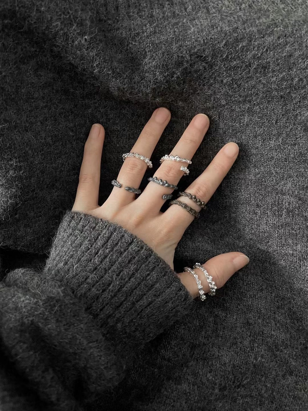 Amazon · Double Coil Snakebone Black Silver Ring — Hand wearing multiple silver rings on a dark textured fabric background