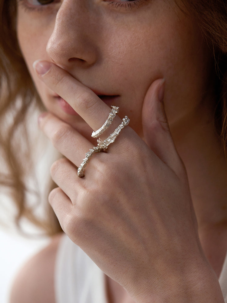 Amazon · Double Coil Snakebone Silver Ring — Close-up of a woman's hand wearing two silver rings with a soft background