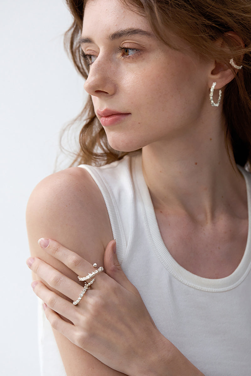 Amazon · Double Coil Snakebone Silver Ring — Woman wearing a silver ring and hoop earrings on a plain background