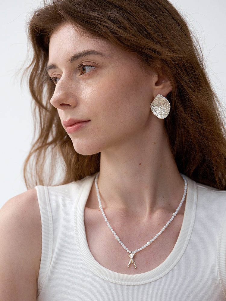 Amazon · Hydrangea Petal Stud Earrings — Woman wearing a necklace and earrings with a plain background