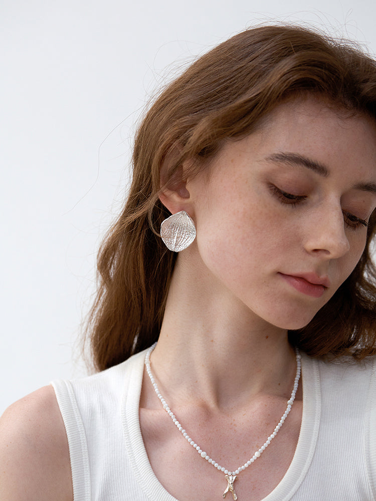 Amazon · Hydrangea Petal Stud Earrings — Woman wearing silver earrings and a necklace against a white background