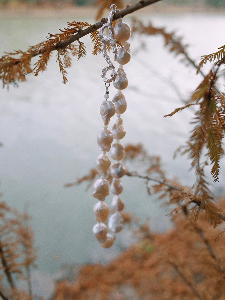 Amazon · Snakebone S-Hook Baroque Pearl Choker Necklace — Pearl necklace hanging from a branch with a blurred natural