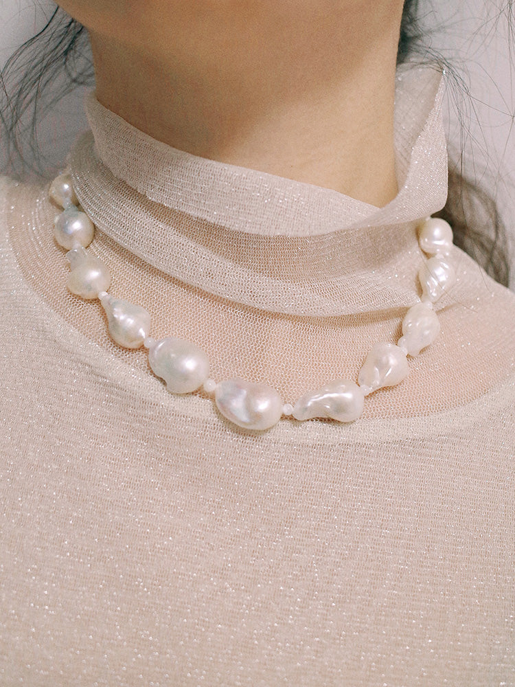 Amazon · Snakebone S-Hook Baroque Pearl Choker Necklace — Pearl necklace worn by a person with a soft focus background