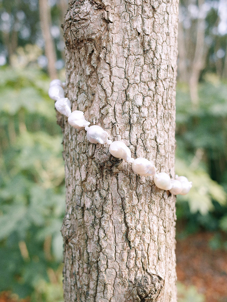 Amazon · Snakebone S-Hook Baroque Pearl Choker Necklace — White beaded necklace draped over a tree trunk with a natural