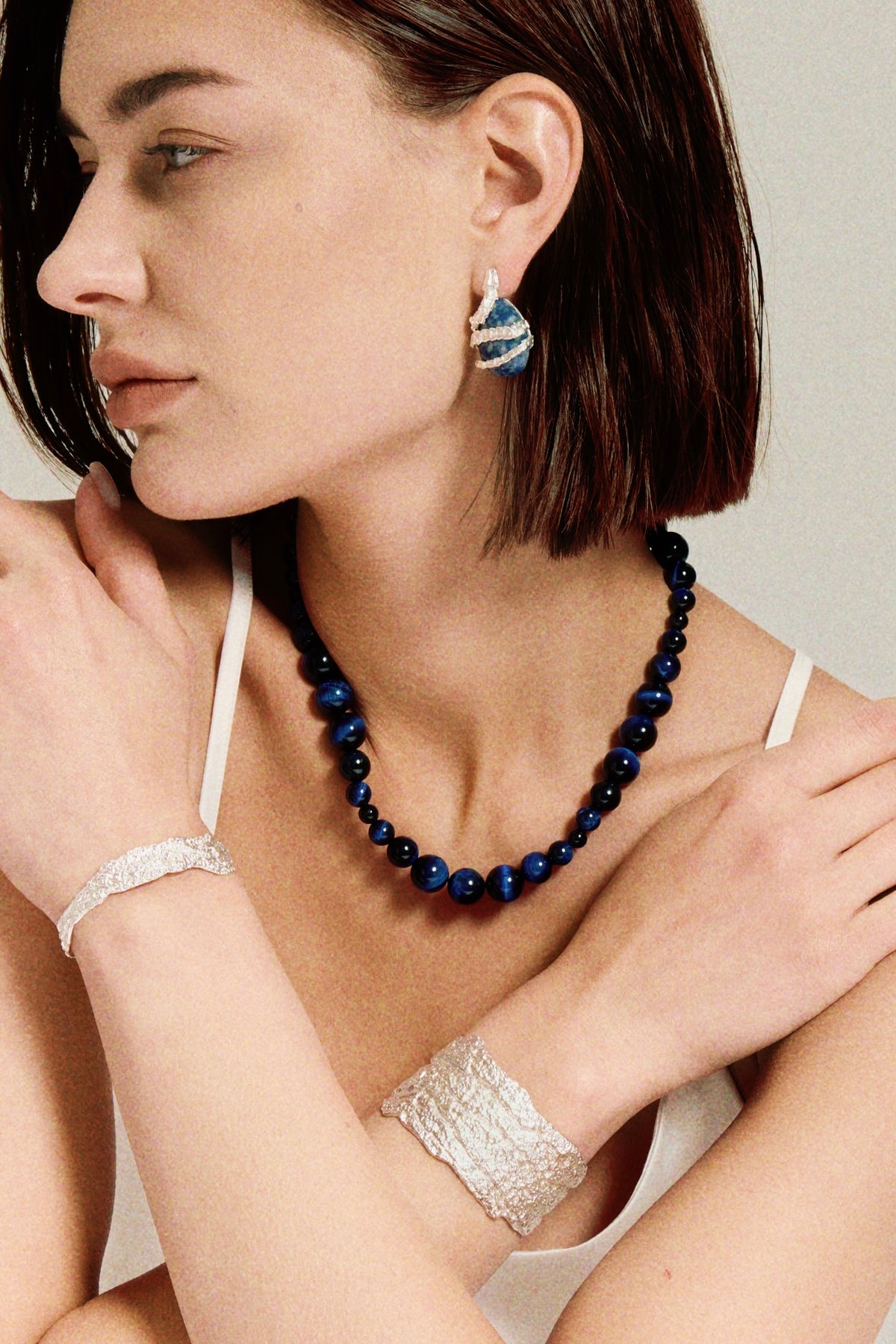 Amazon · Snakebone S-Hook Tiger’s Eye Choker Necklace — Woman wearing a blue beaded necklace and silver earrings and bracelet