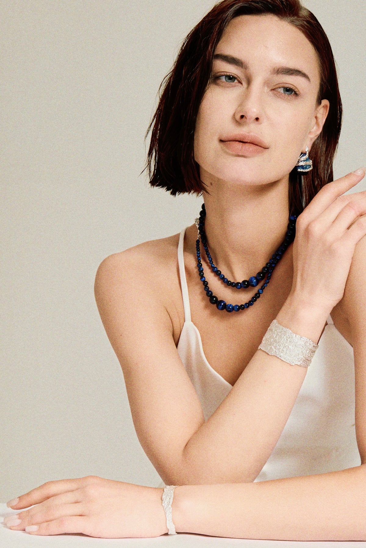Amazon · Snakebone S-Hook Tiger’s Eye Choker Necklace — Woman wearing a necklace, bracelet, and earrings on a neutral