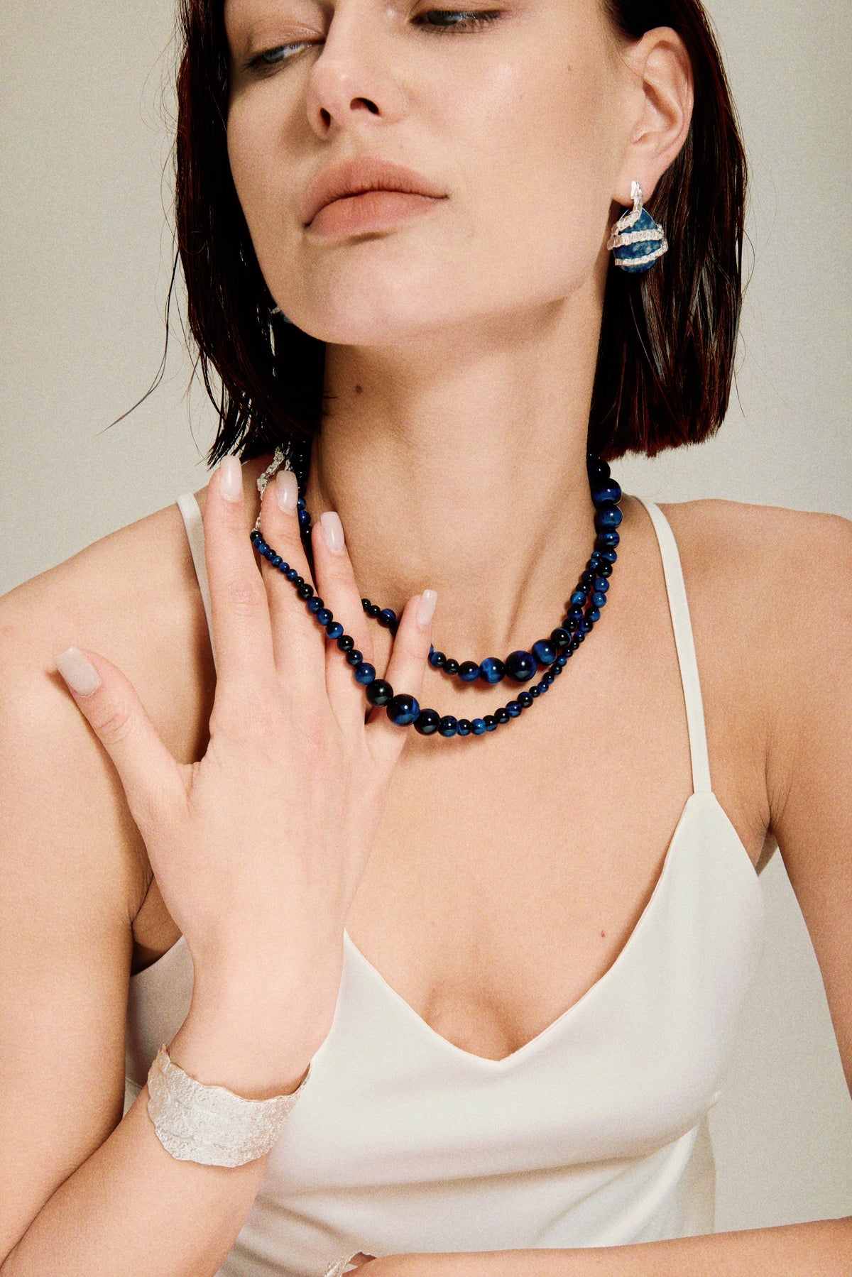 Amazon · Snakebone S-Hook Tiger’s Eye Long Necklace — Woman wearing a blue beaded necklace and white top against a neutral