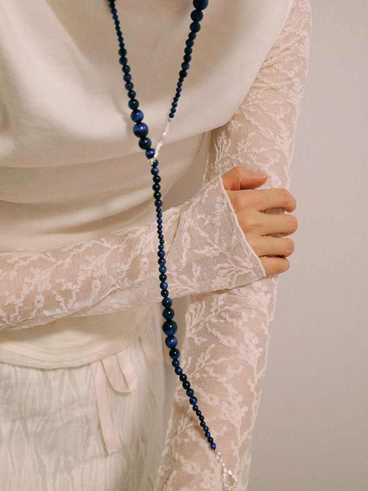 Amazon · Snakebone S-Hook Tiger’s Eye Long Necklace — Person wearing a long blue beaded necklace with a neutral background