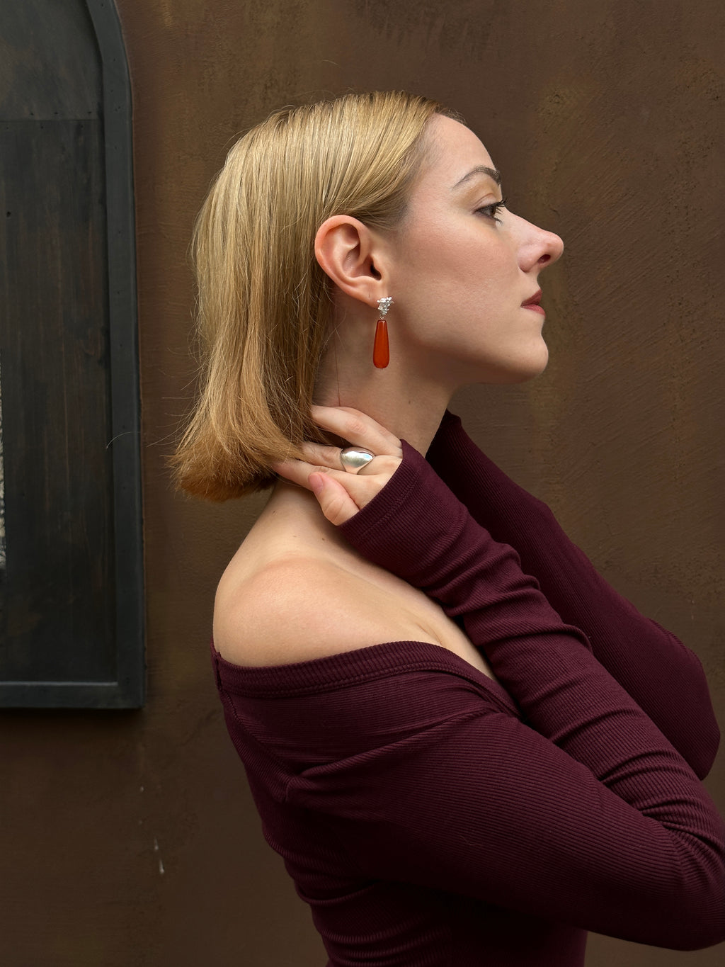 Amazon · Spine & Quartz Raindrop Earrings — Woman wearing a burgundy top against a brown wall