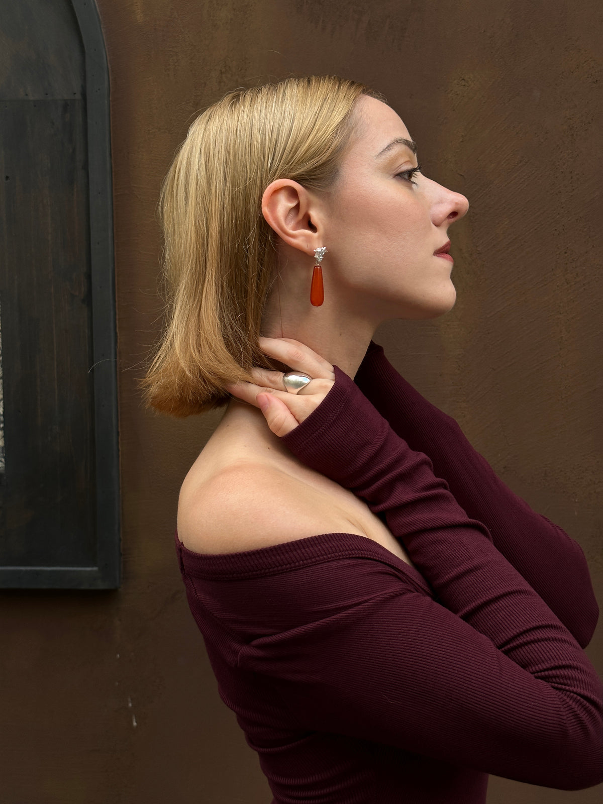 Amazon · Spine & Quartz Raindrop Earrings — Woman wearing a burgundy top against a brown wall