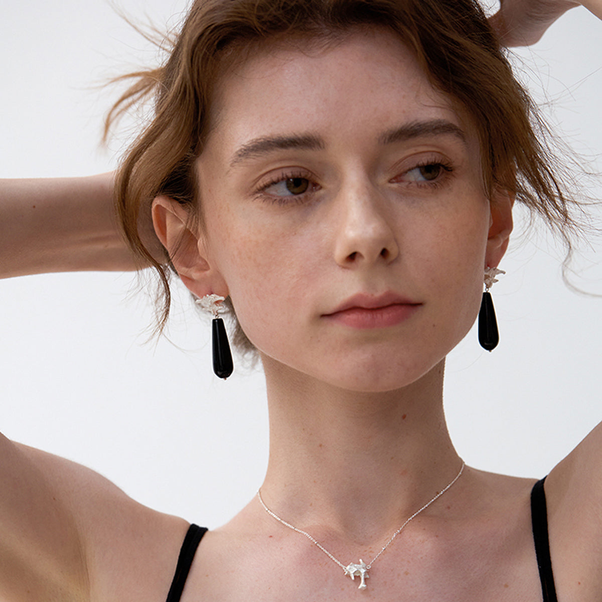 Amazon · Spine & Quartz Raindrop Earrings — Woman wearing black earrings and a necklace with a white background