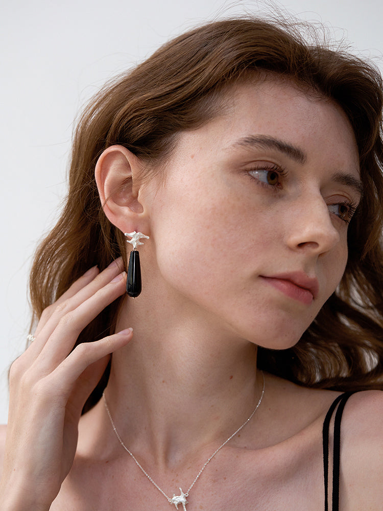 Amazon · Spine & Quartz Raindrop Earrings — Woman wearing a black earring and necklace against a neutral background