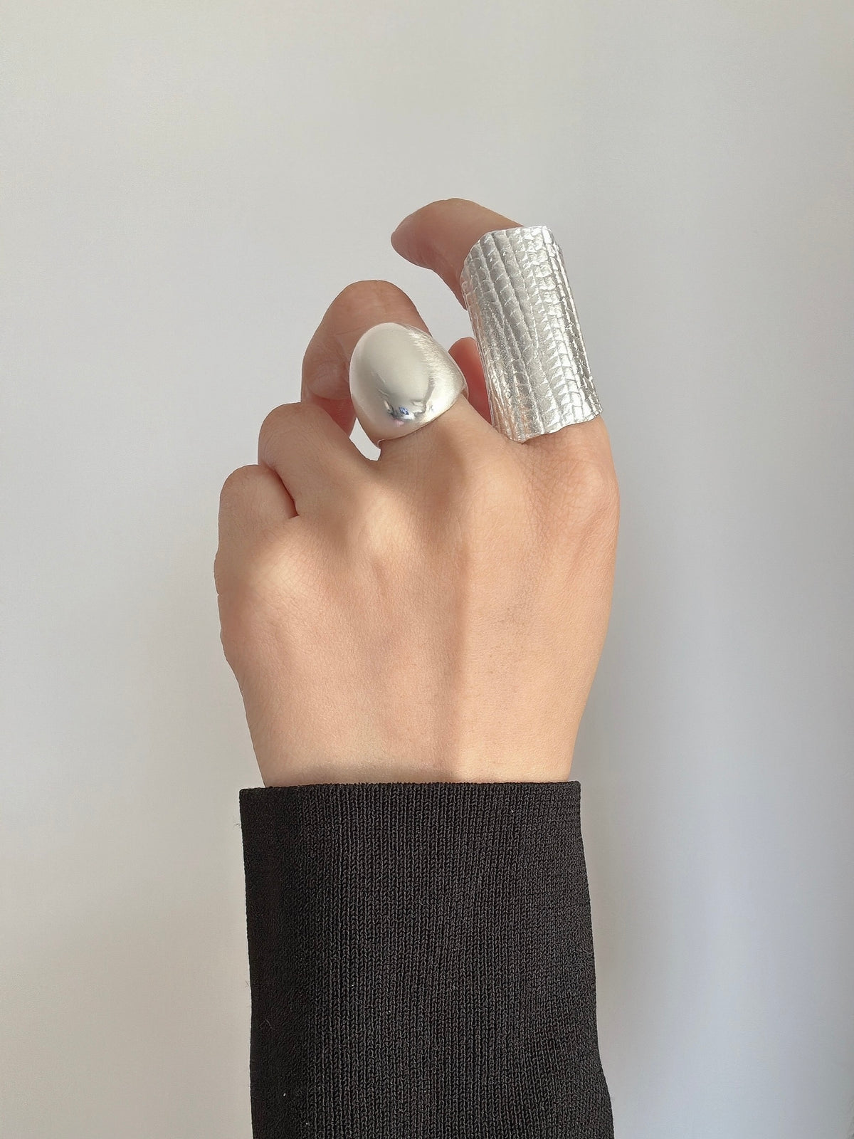 Amazon · Tilted Tower Wide Band Ring — Hand wearing a silver ring on a plain background