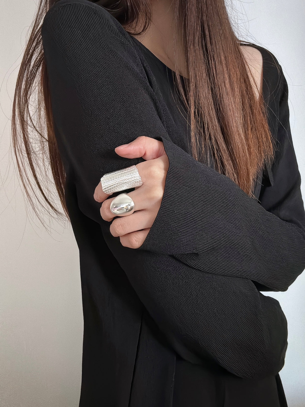 Amazon · Tilted Tower Wide Band Ring — Person wearing a black outfit with silver rings on a plain background