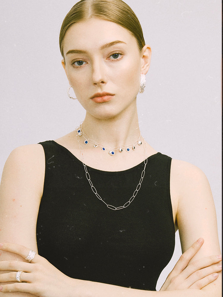 Amazon · Tree Grain Hoop Earrings — Woman wearing a black sleeveless top with layered necklaces against a plain background