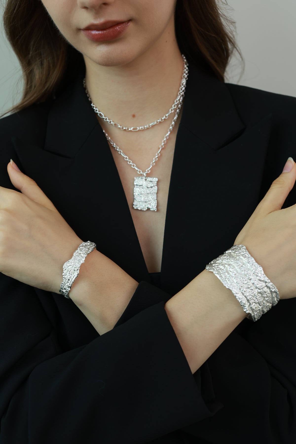 Amazon Tree Grain — Woman wearing silver jewelry including a bracelet and necklace against a black background
