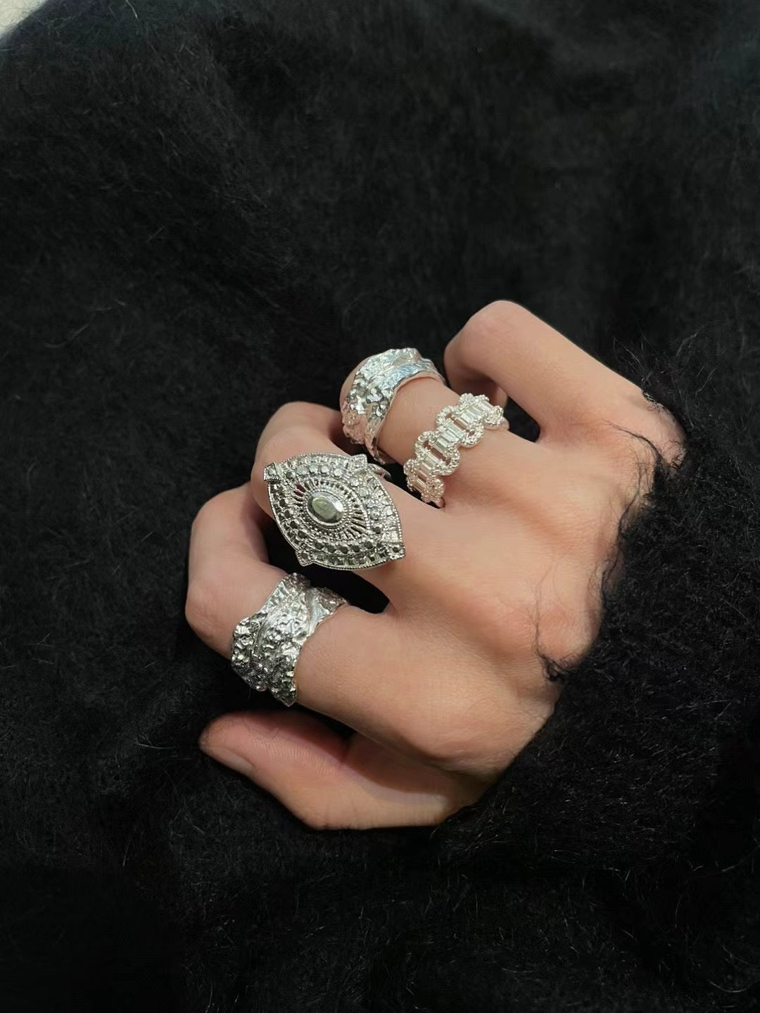 Amazon · Tree Grain Wide Band Silver Ring — Hand wearing multiple silver rings on a black background