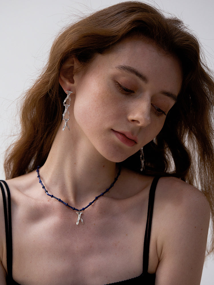 Amazon · Wishbone Long Earrings — Woman wearing a necklace with a small pendant against a neutral background