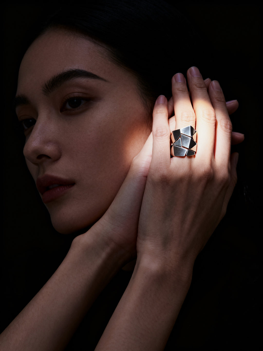 Woman wearing a geometric ring with a dark background
