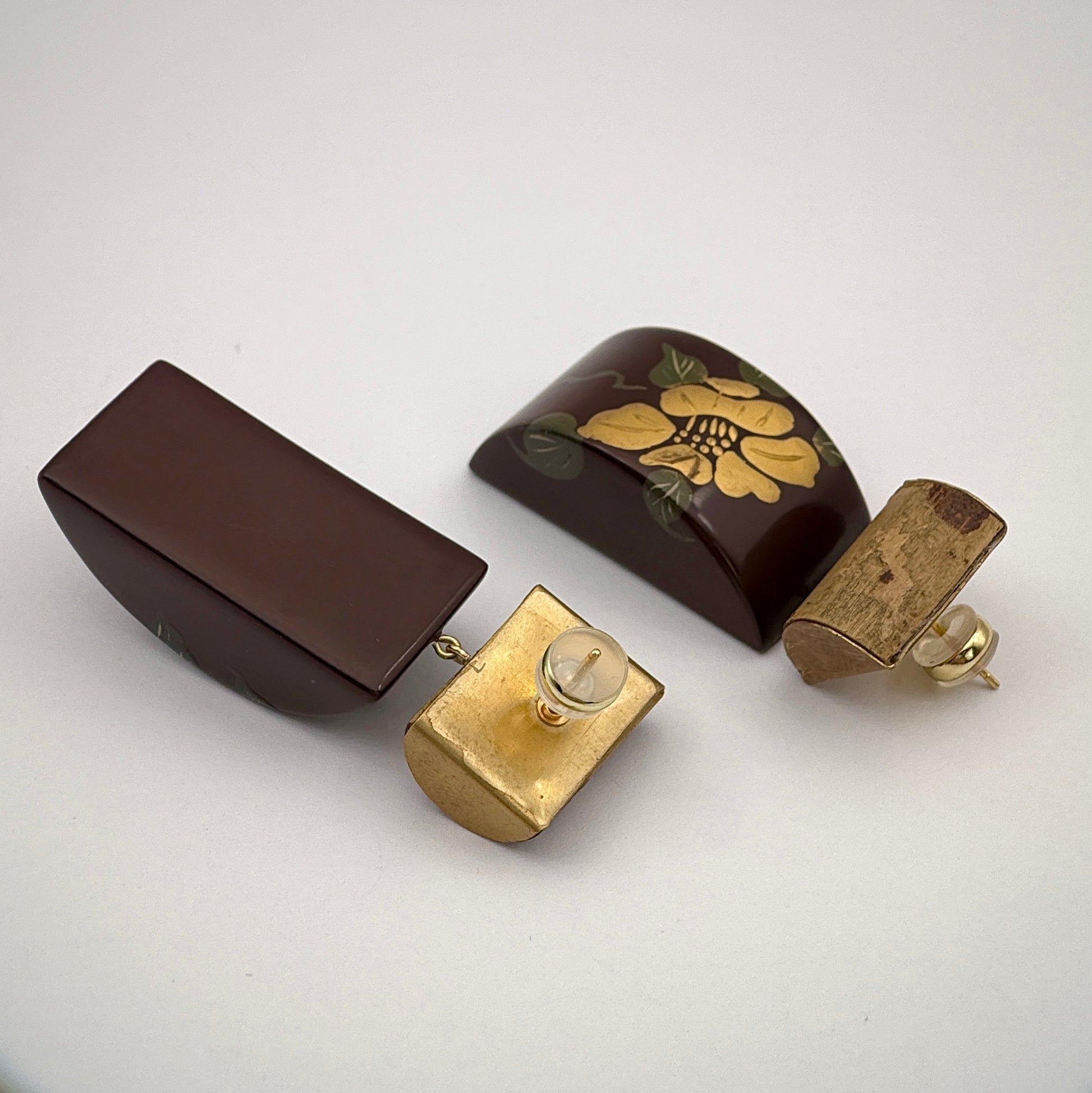 Set of vintage-style jewelry pieces including a brown box, gold earring, and decorative item on a white background.