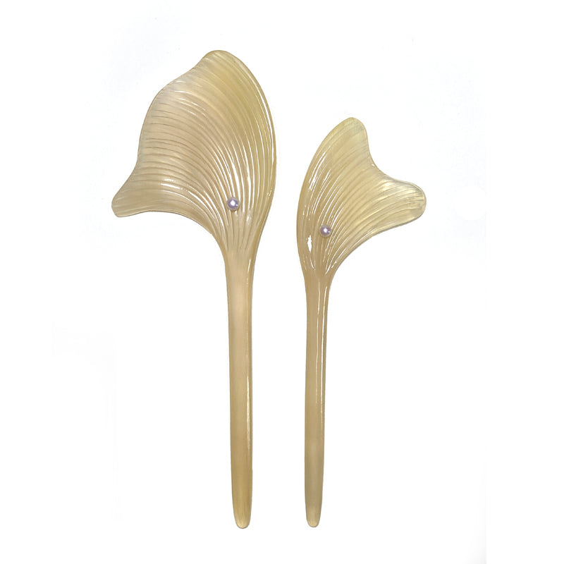Two beige hair accessories shaped like leaves on a white background