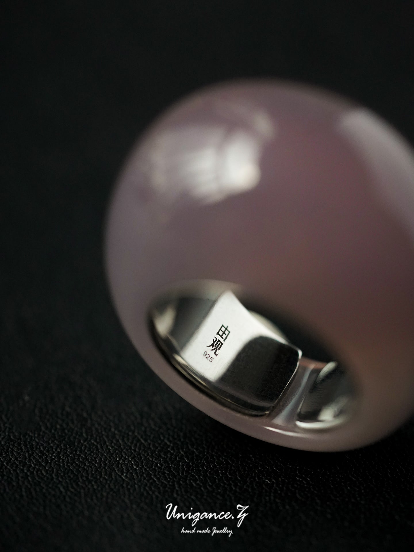 Close-up of a silver ring with a purple gemstone on a black background