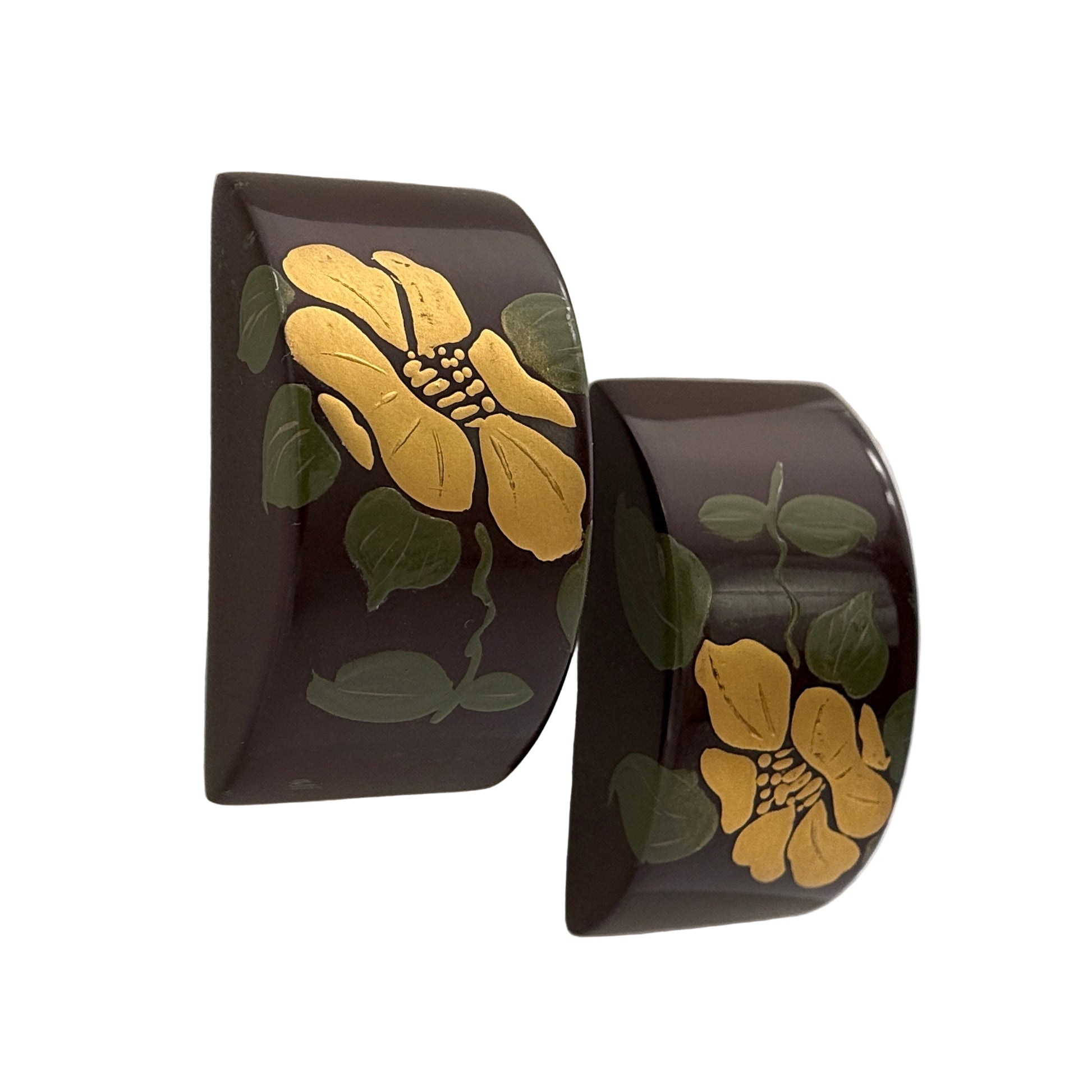 Pair of black cuff bracelets with yellow floral designs on a white background