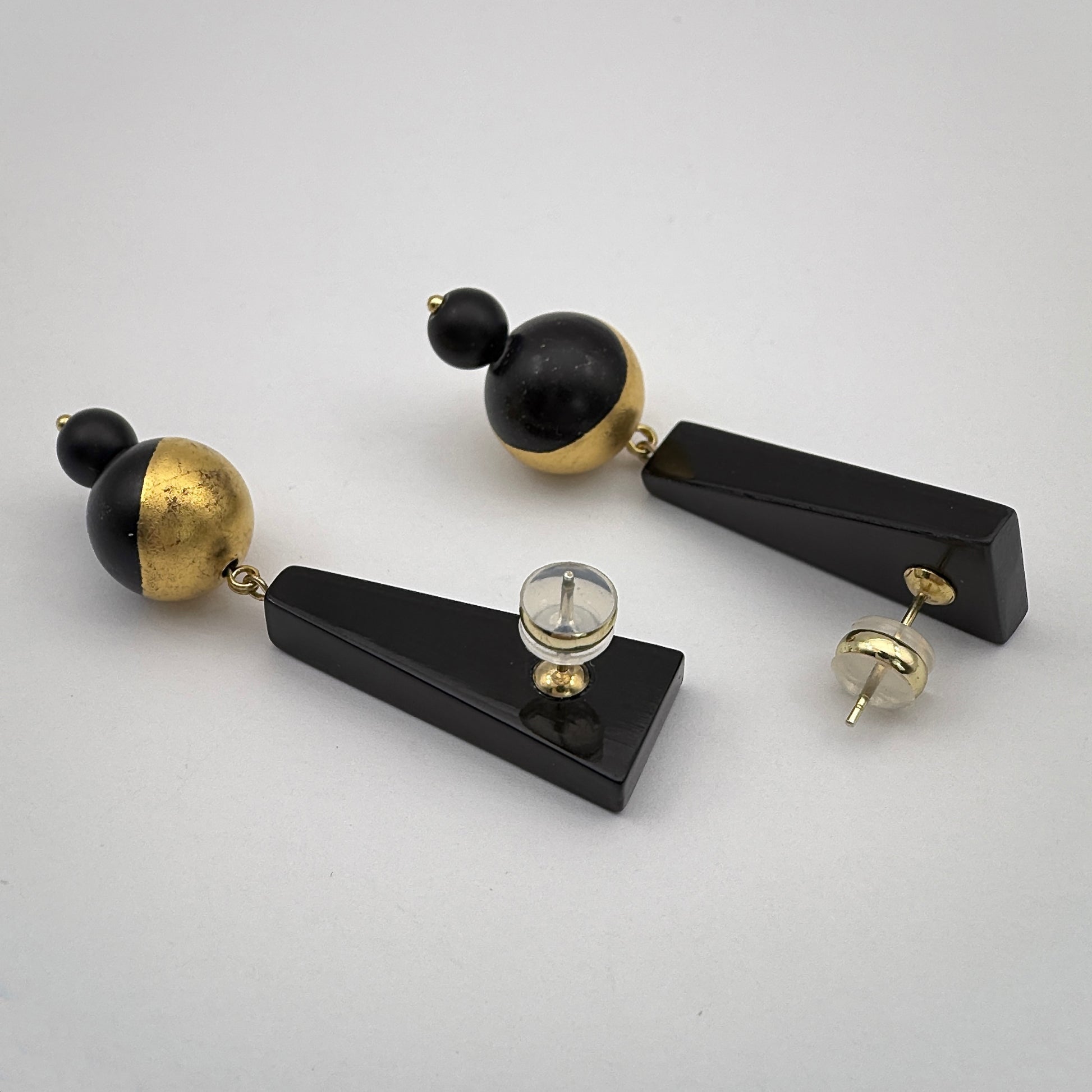 Pair of black and gold earrings on a light gray background