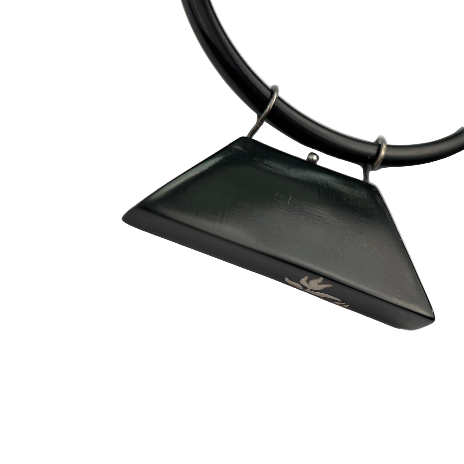 Black triangular pendant on a black cord against a white background