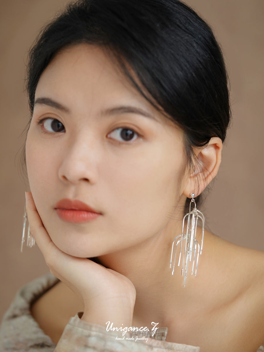 Woman wearing long, dangling earrings with a neutral background