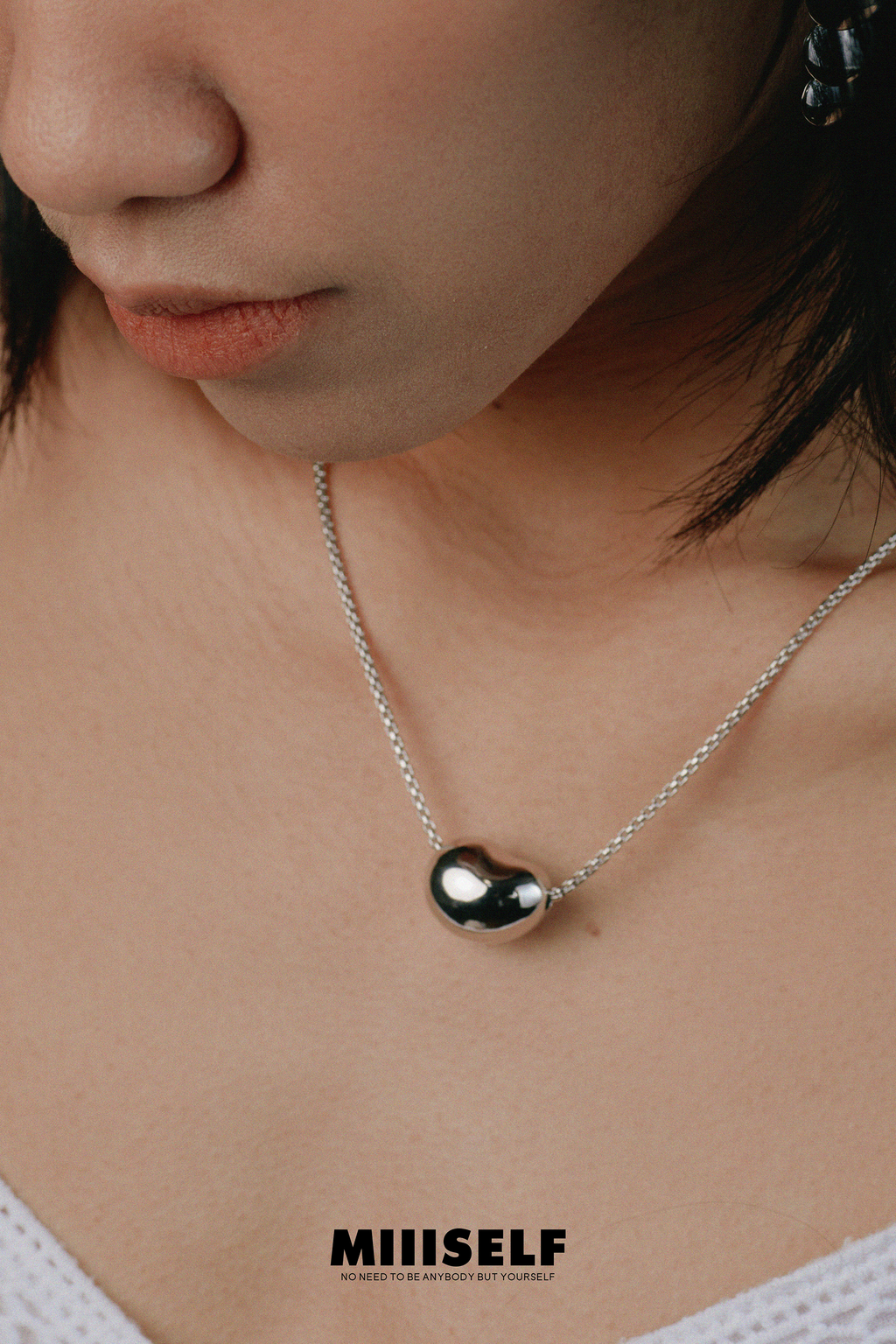 Asymmetric Heart Necklace — Close-up of a person wearing a necklace with a pendant, brand 'MIIISELF' visible.