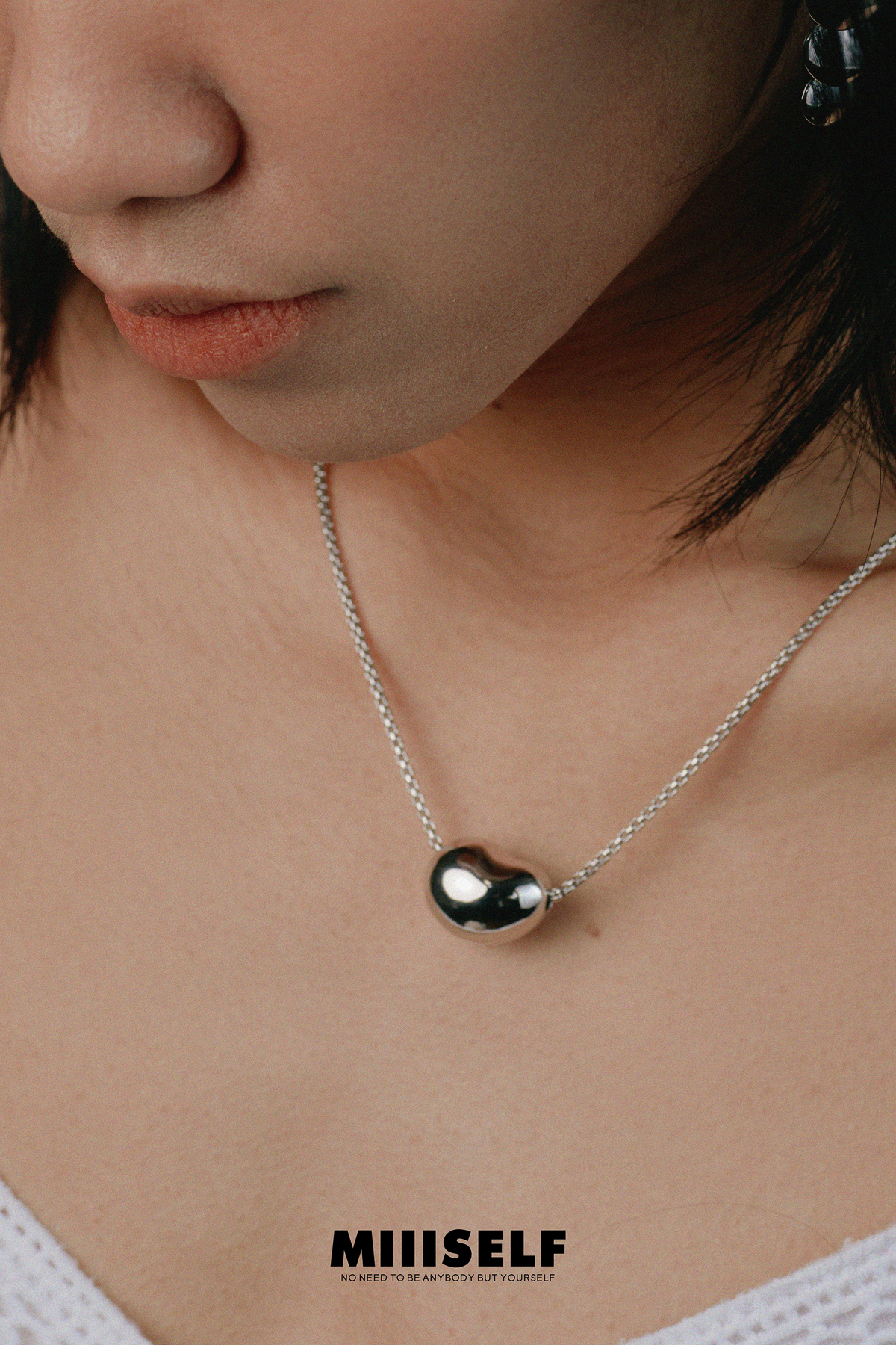 Asymmetric Heart Necklace — Close-up of a person wearing a necklace with a pendant, brand 'MIIISELF' visible.