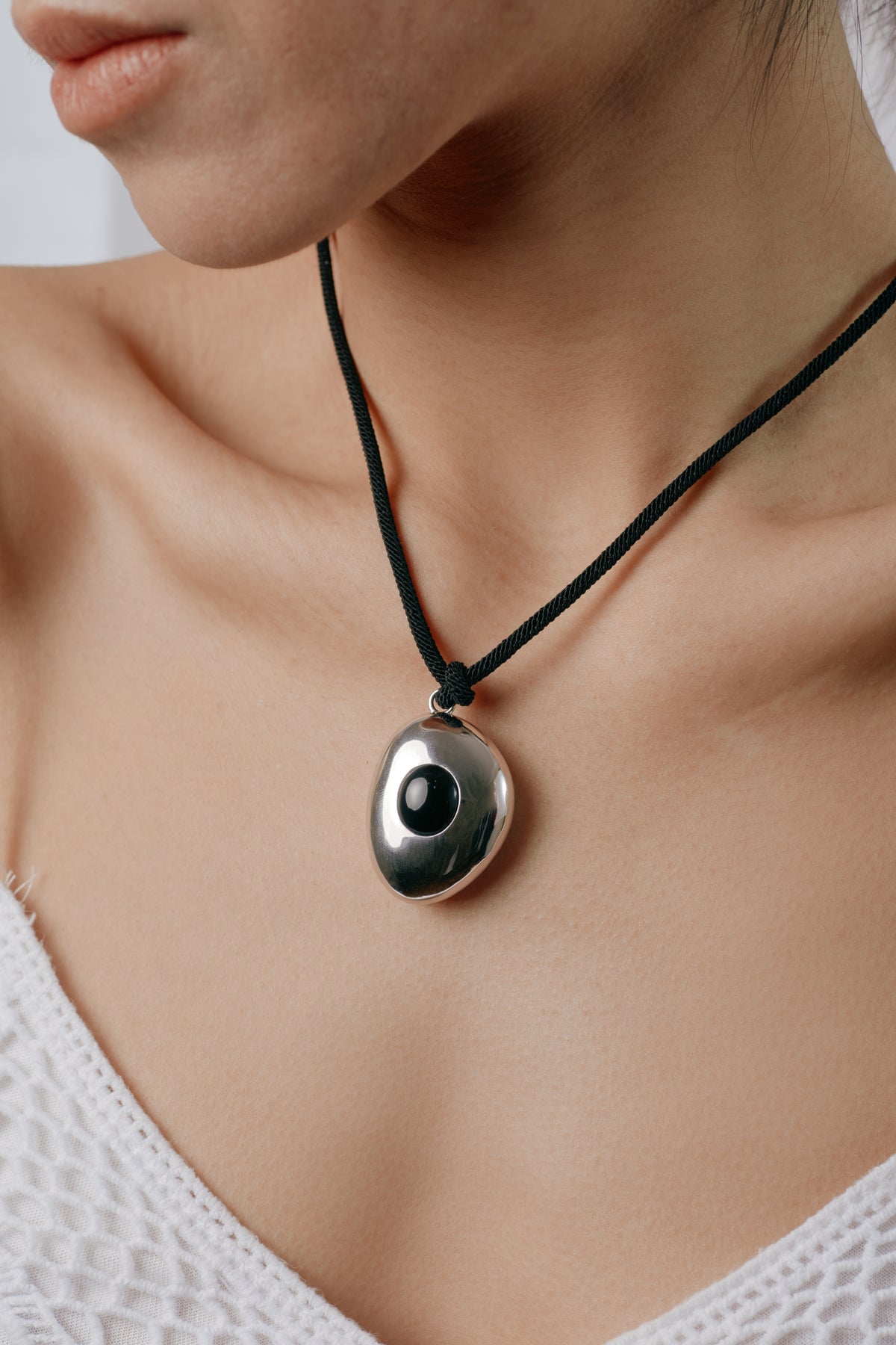 Avocado Mirror Pendant Necklace — Necklace with a pendant worn by a person, focusing on the necklace.