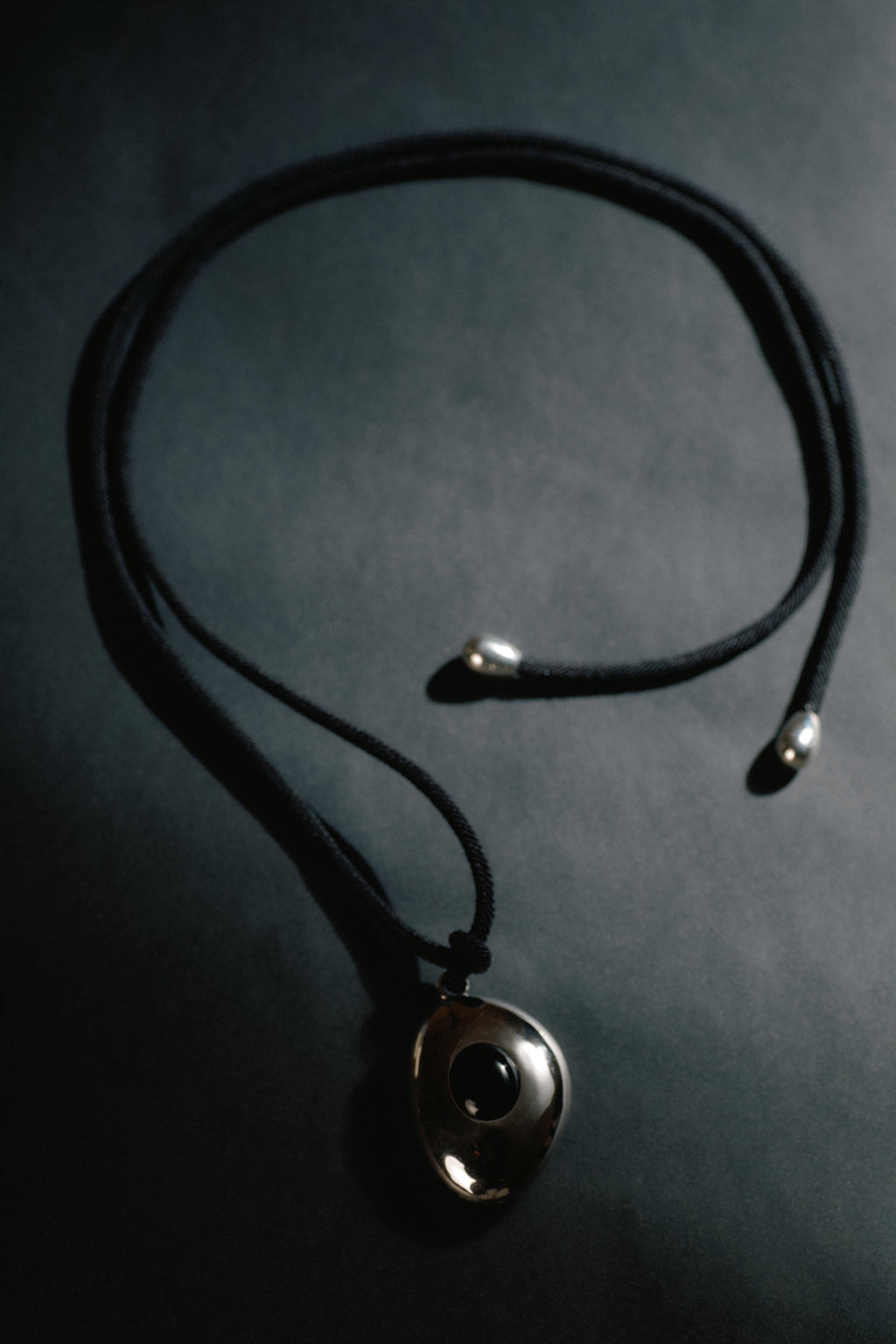 Avocado Mirror Pendant Necklace — Necklace with a round pendant on a dark background