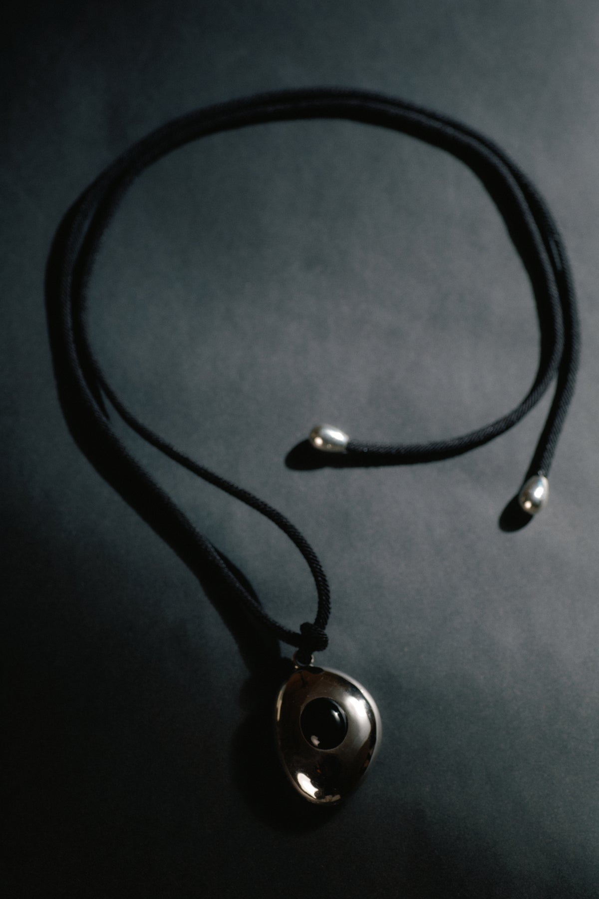 Avocado Mirror Pendant Necklace — Necklace with a round pendant on a dark background