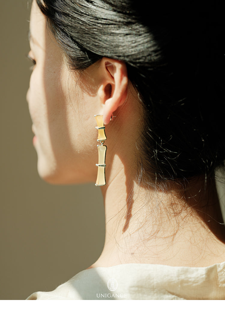 Bamboo Branch Drop Earrings — Close-up of a person wearing gold earrings with a neutral background
