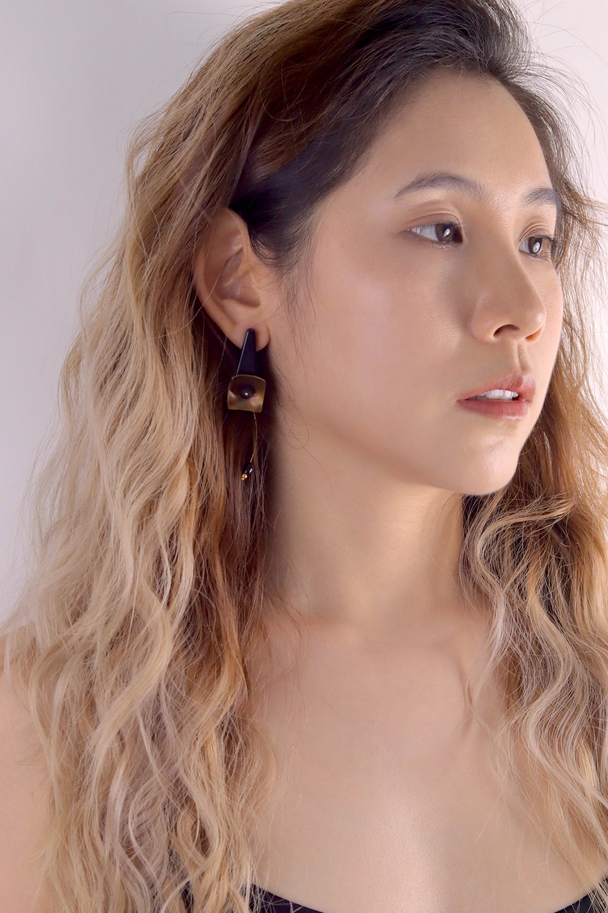 Black Hibiscus Lacquer Quasi-Maki-e Earrings — Woman wearing gold earrings with a neutral background