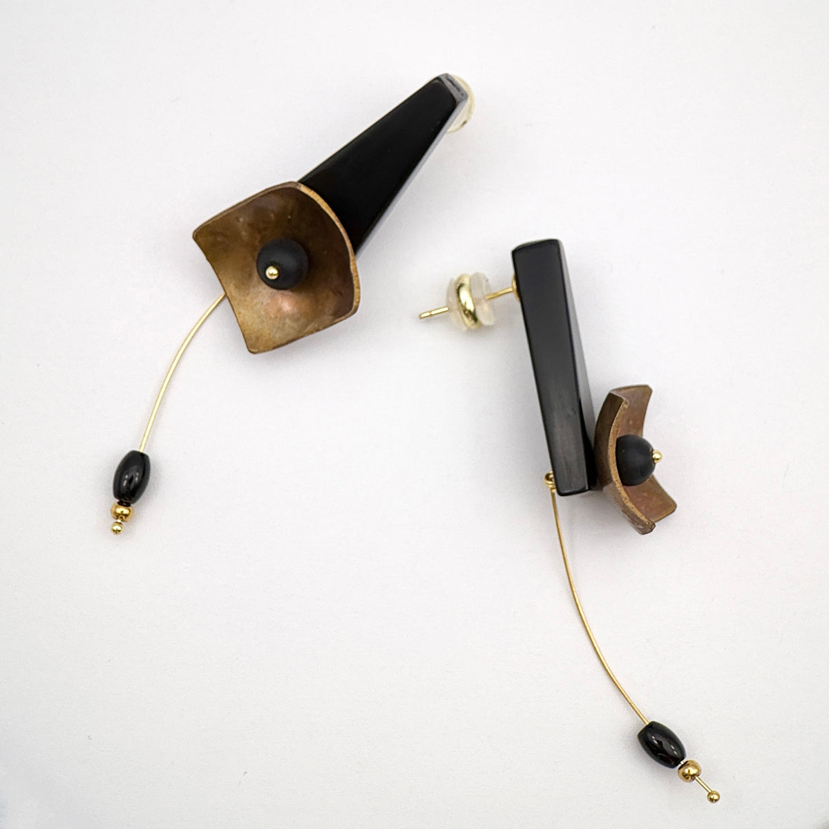 Black Hibiscus Lacquer Quasi-Maki-e Earrings — Pair of earrings with black, gold, and brown elements on a white background