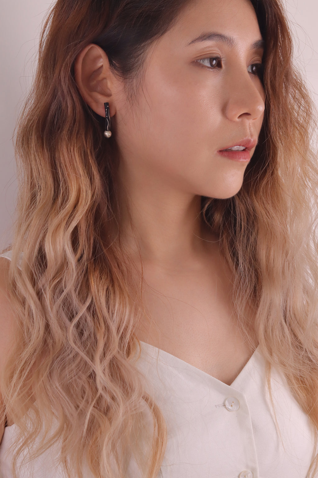Black Orchid Lacquer Quasi-Maki-e Earrings — Woman with wavy hair wearing a white top against a neutral background
