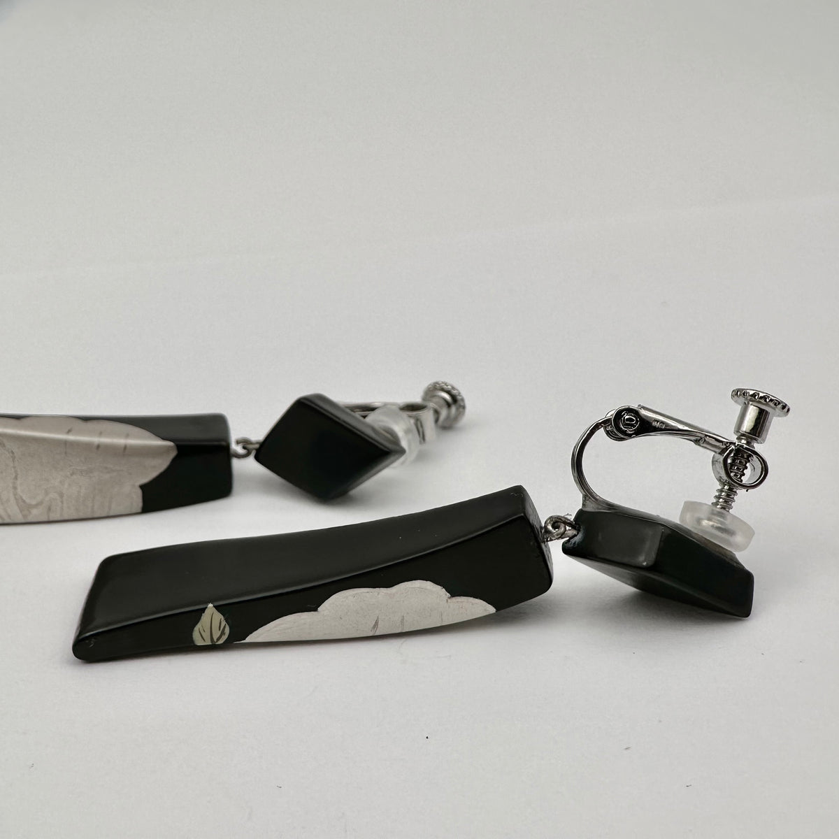 Black Peony Lacquer Quasi-Maki-e Earrings — Black and silver tie clip on a white background