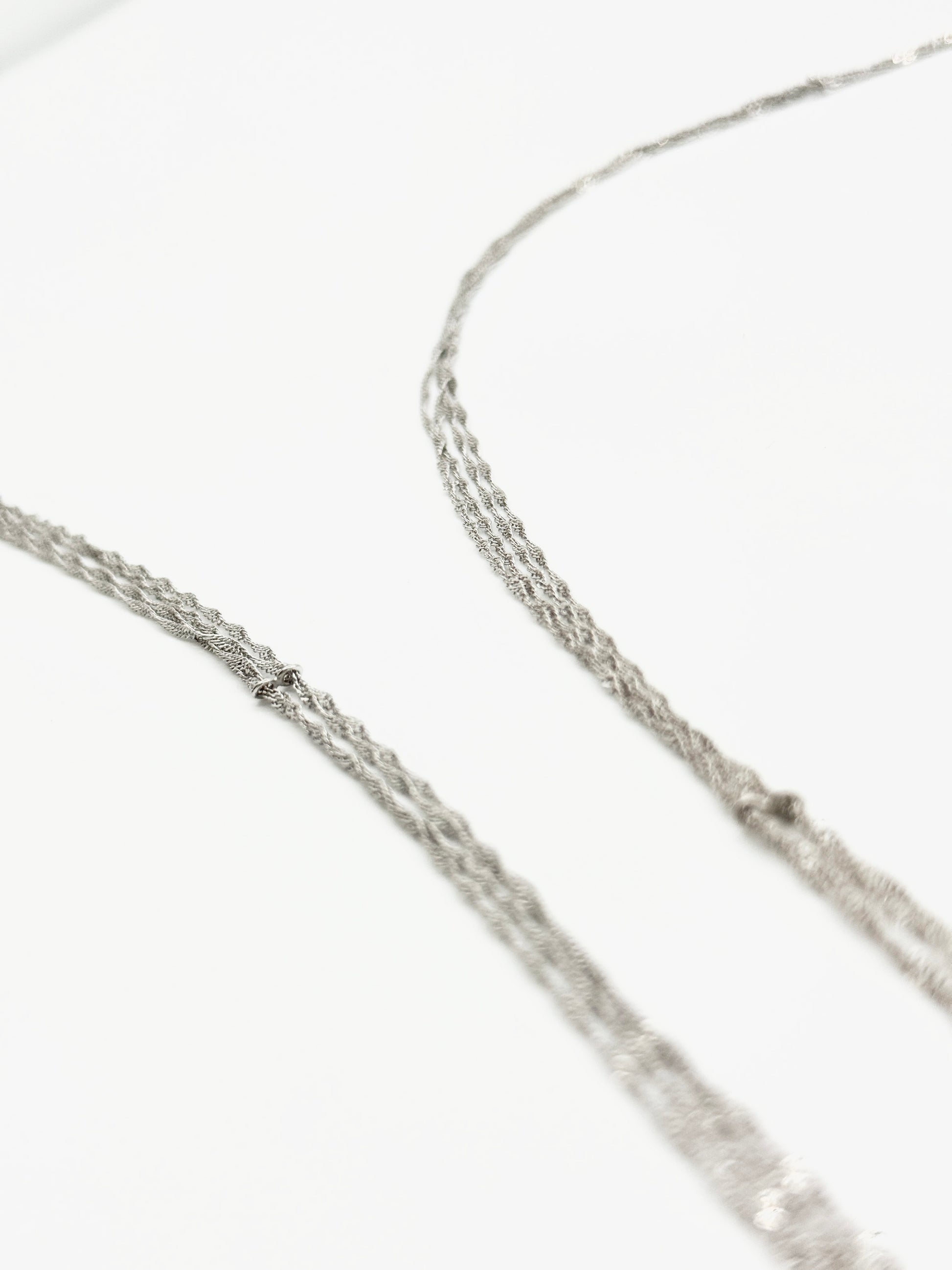Close-up of a silver chain necklace on a white background