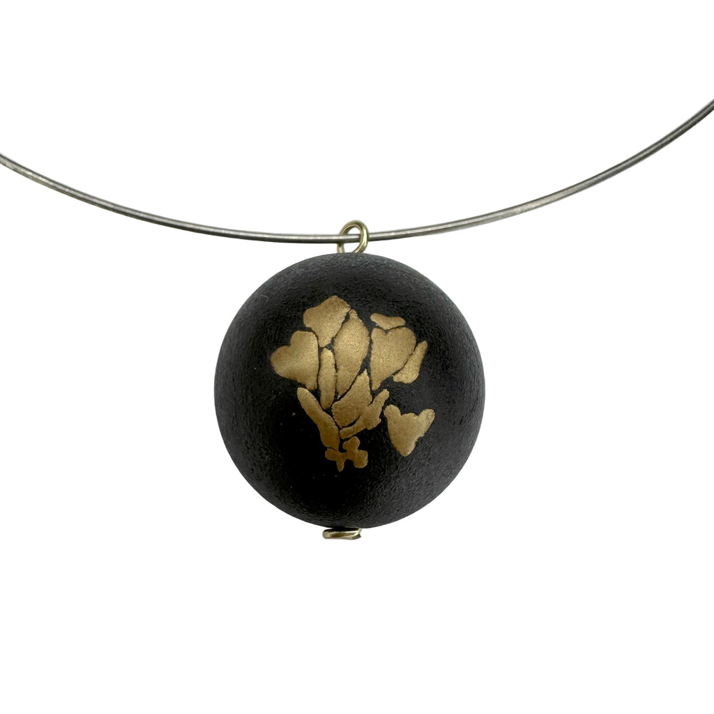 Bloom and Fade Magnolia Lacquer Quasi-Maki-e Necklace — Black pendant with gold floral design on a white background