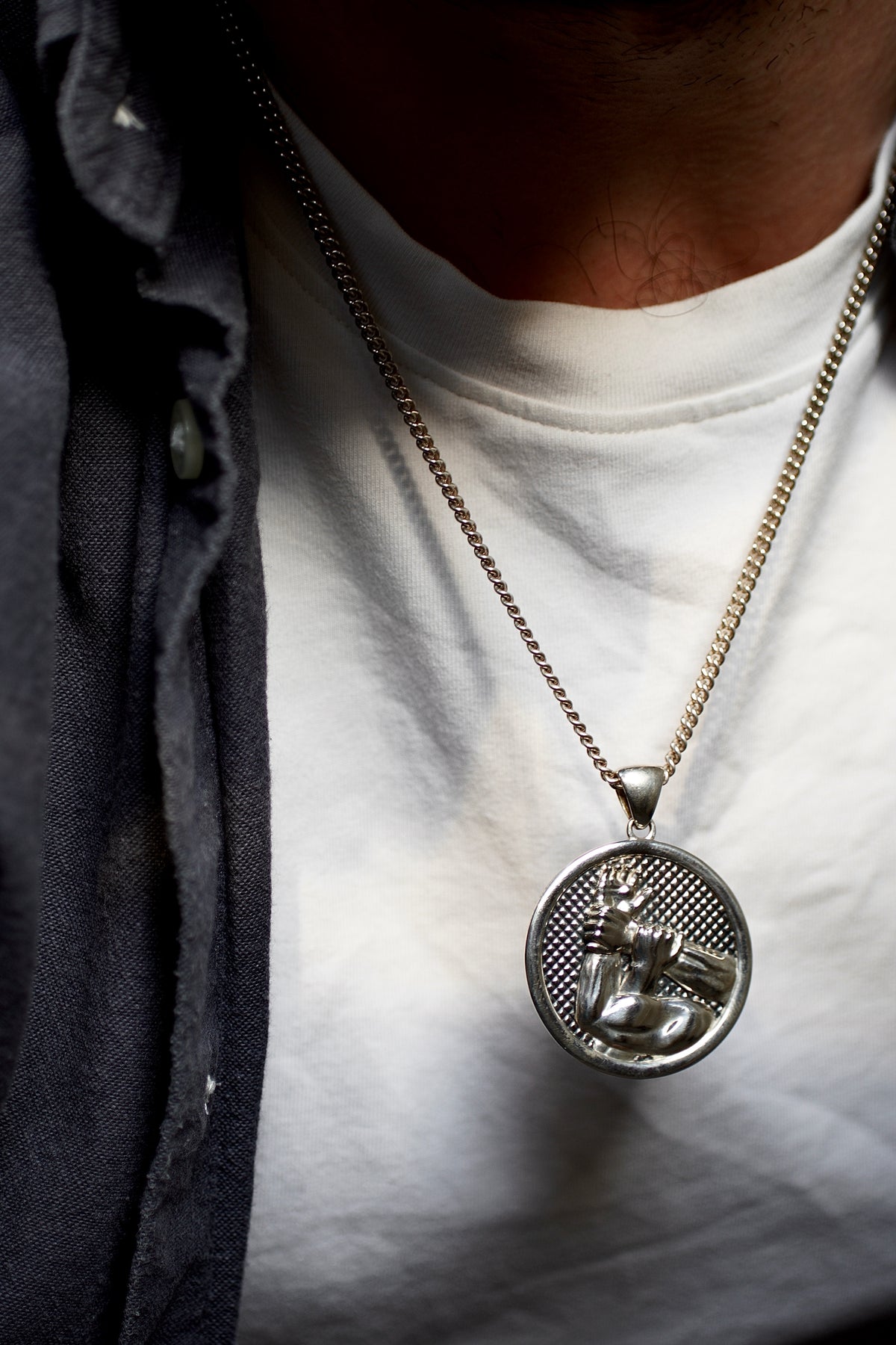 Brazilian Jiu-Jitsu Americana Necklace — Close-up of a person wearing a necklace with a pendant on a white shirt.
