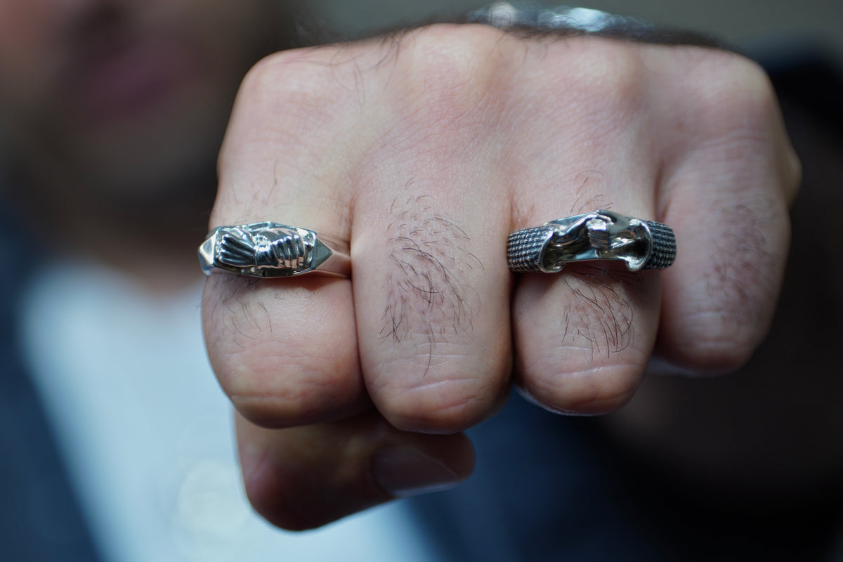 Brazilian Jiu Jitsu Grip Ring — Close-up of a fist wearing two silver rings with intricate designs.