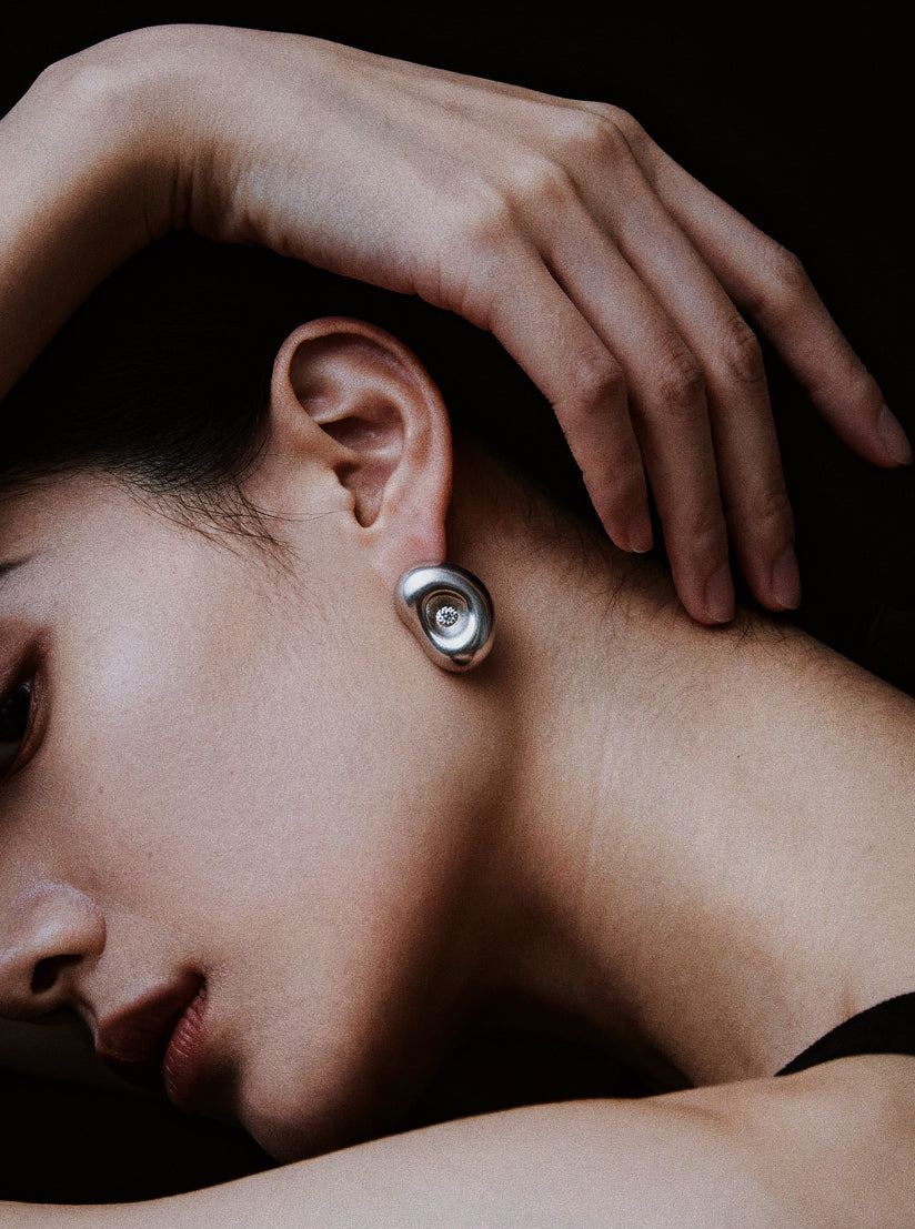 Breathing Geometry · Moissanite & Silver Earrings — Close-up of a person wearing a silver earring with a dark background