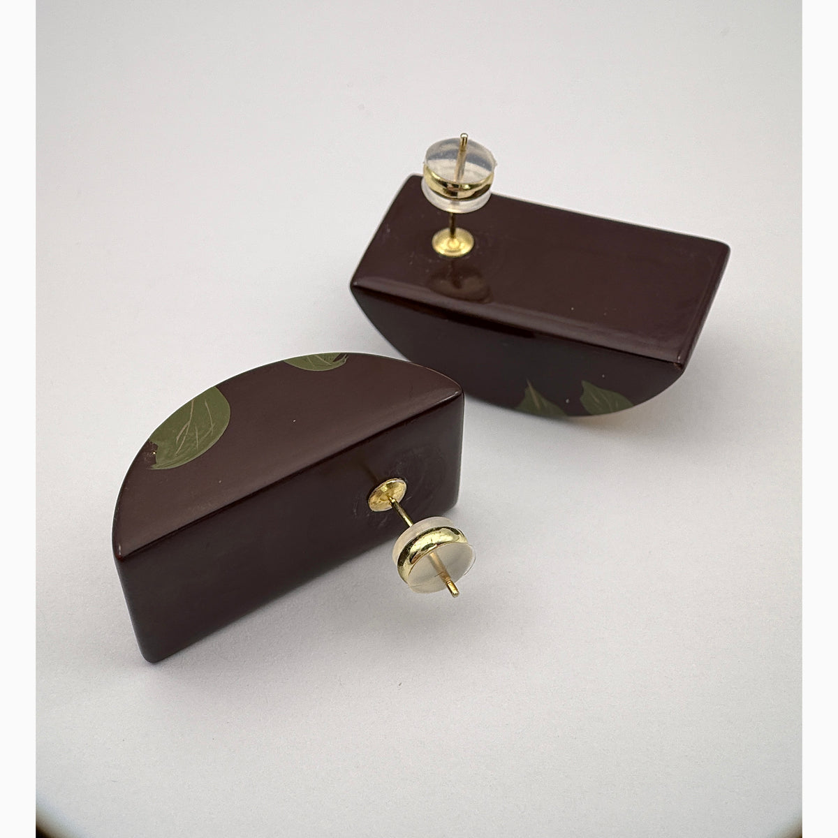 Camellia Lacquer Quasi-Maki-e Earrings — Two brown decorative boxes with gold knobs on a white background