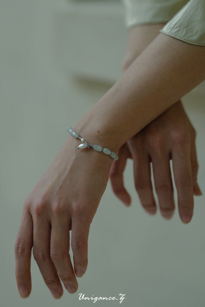 Close-up of a hand wearing a silver bracelet on a neutral background
