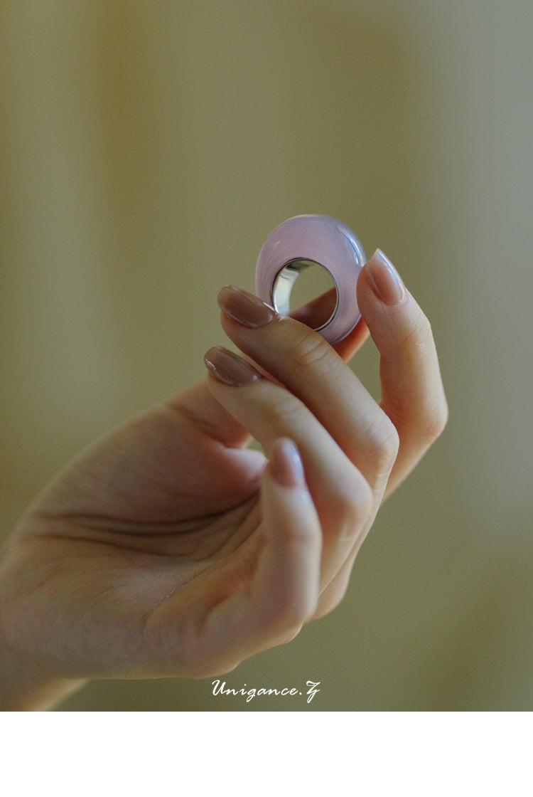 Hand holding a small pink object against a blurred background
