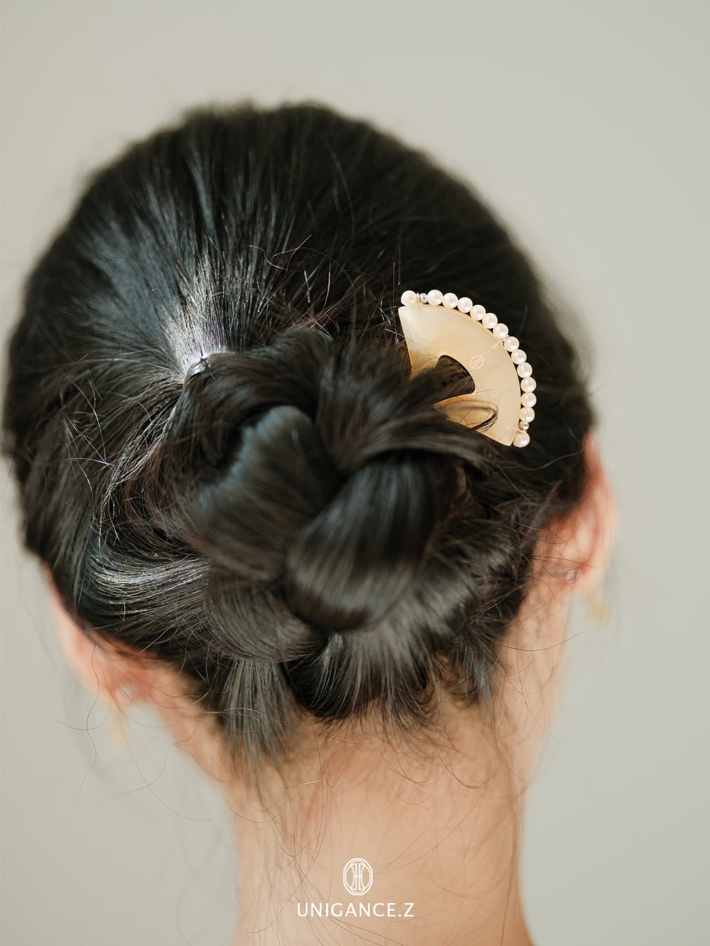 Hair bun with a decorative hair clip on a neutral background